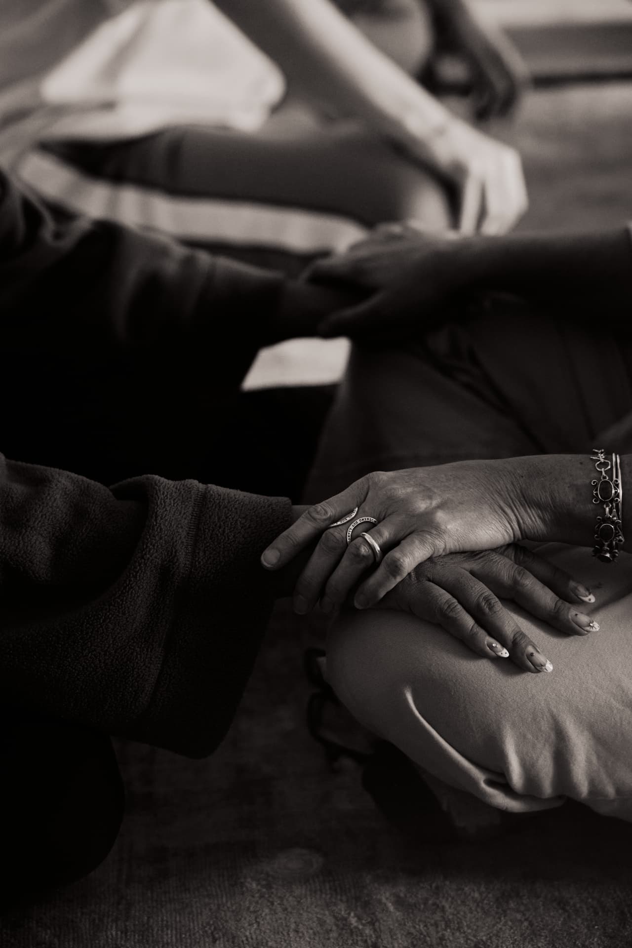 One woman's hand resting on another's during a breathwork session