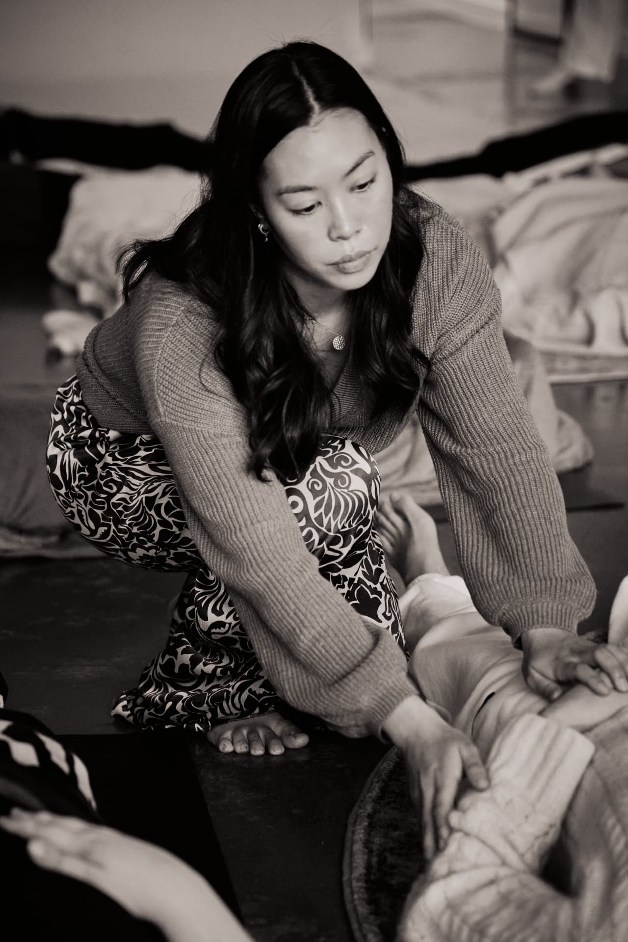 Bridg kneeling beside a woman, hands resting on her, during a breathwork session